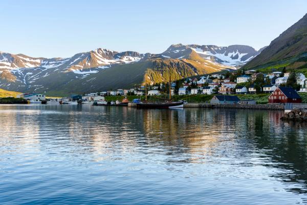 a small town on the shore of a lake with mountains in the background .