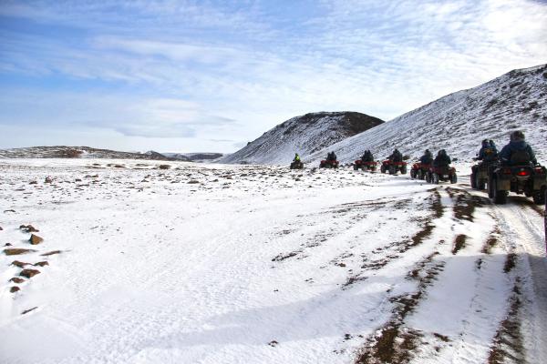 a group of people are riding atvs down a snowy road .