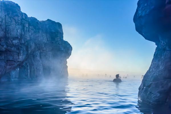a person is swimming in Sky Lagoon hot spring surrounded by rocks