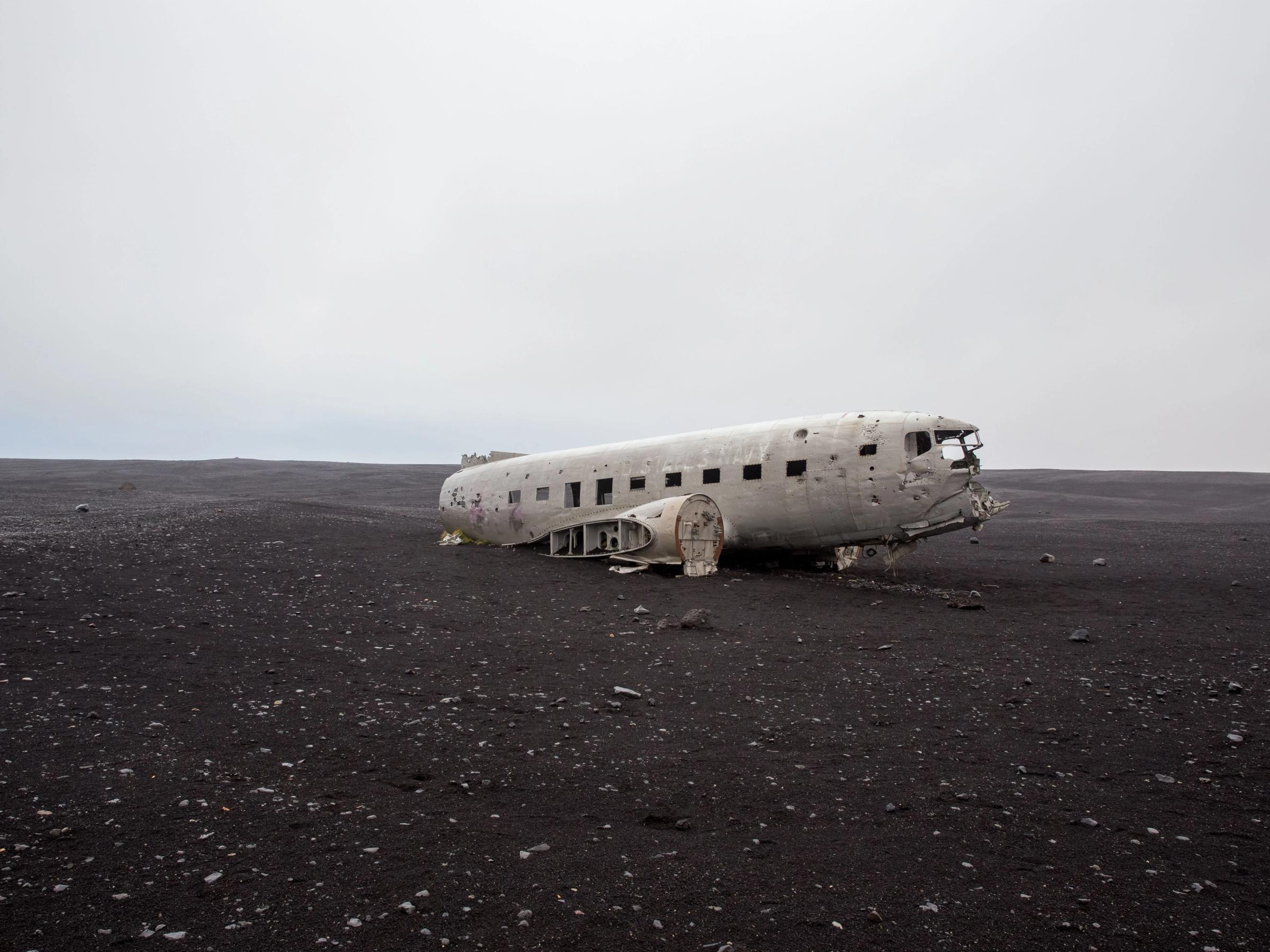 Sólheimasandur Plane Wreck A white plane wreck sits on a vast black sand plain under a grey sky.