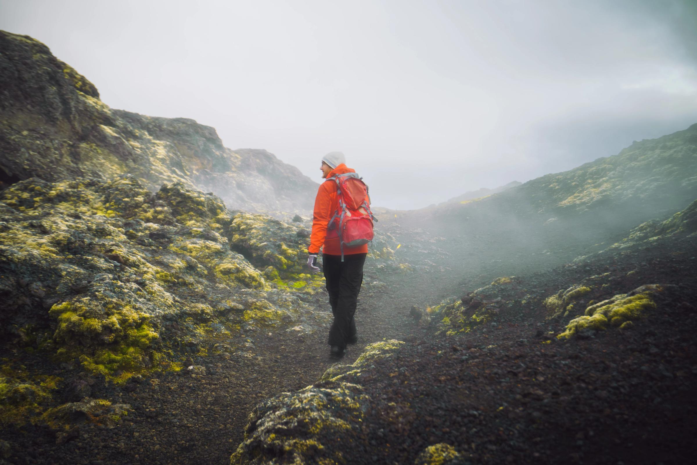una persona con una mochila está caminando por un sendero en las montañas.