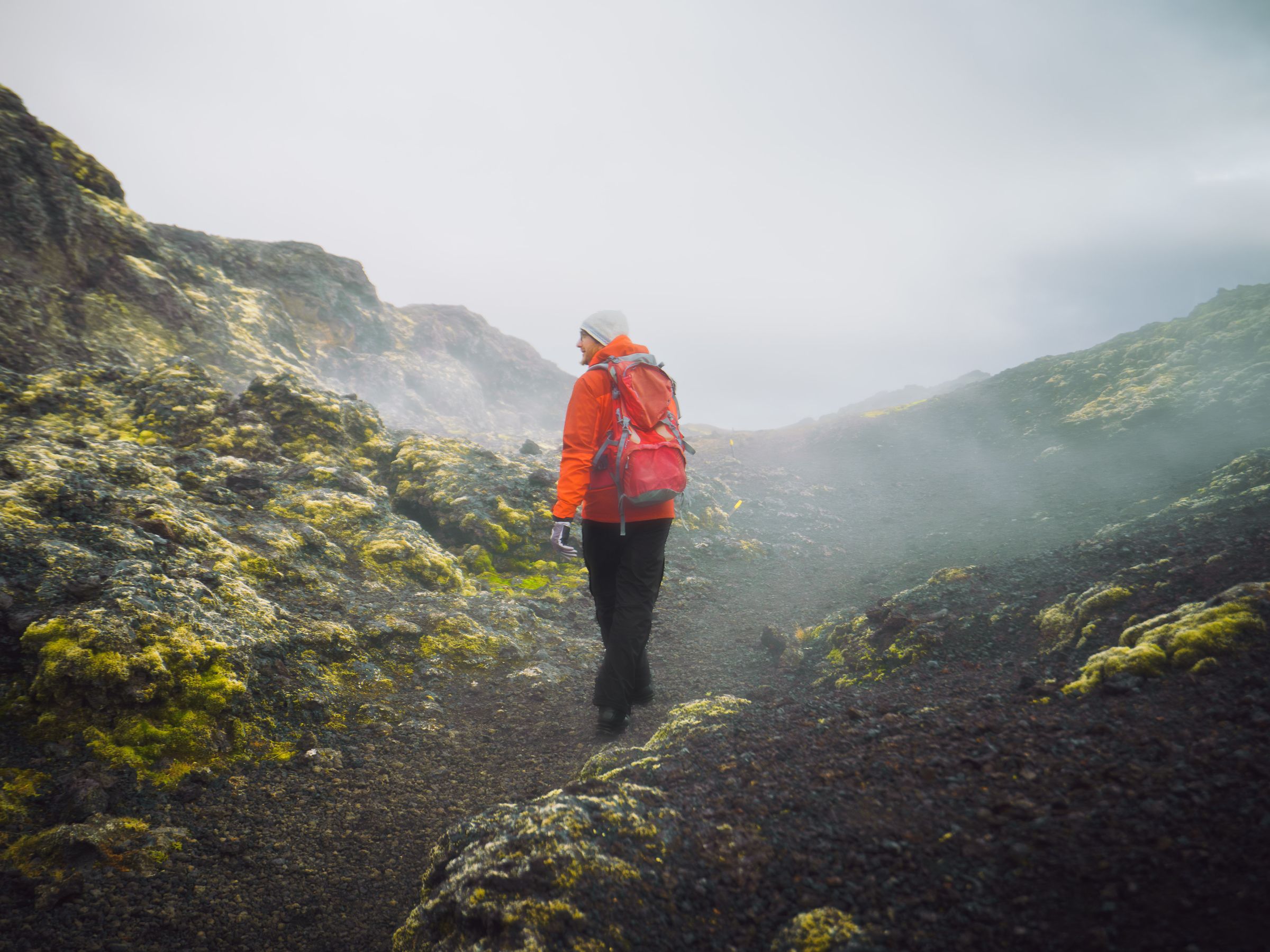 una persona con una mochila está caminando por un sendero en las montañas.