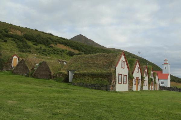 Casas tradicionales de turba y una iglesia blanca construida en una ladera verde.