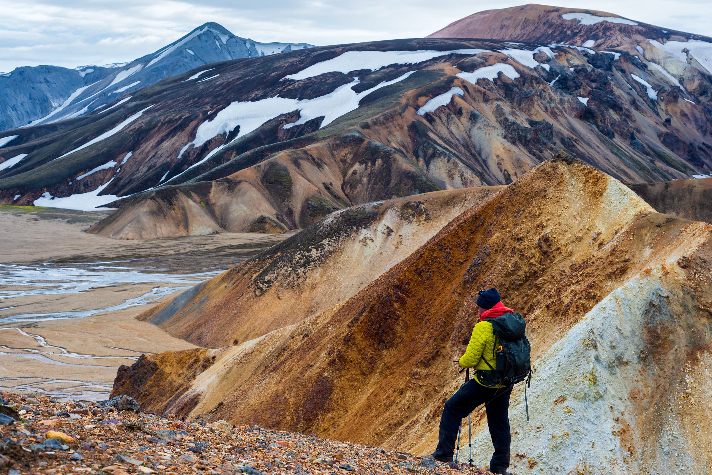 a man with a backpack is standing on top of a mountain in iceland.