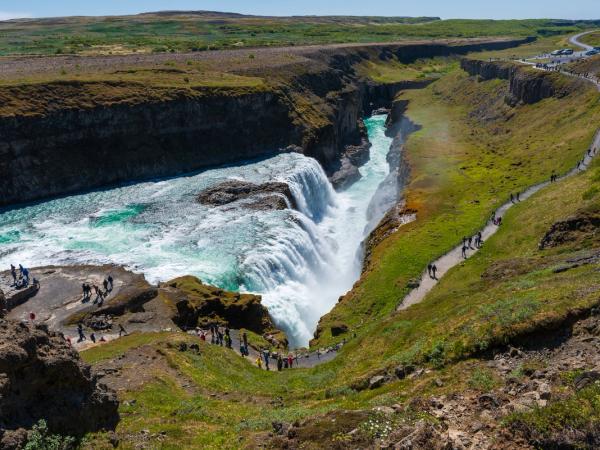 a group of people are walking down a path towards a waterfall .