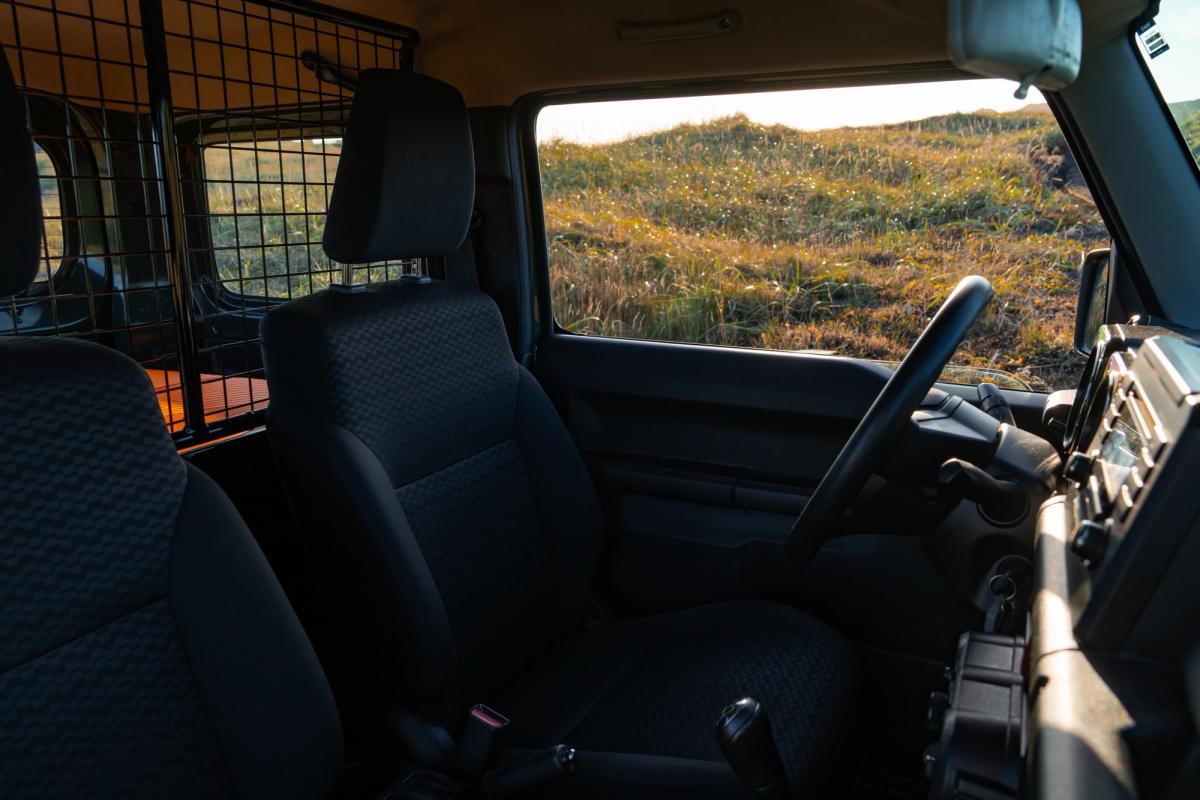 Suzuki Jimny mit manuell verstellbaren Vordersitzen, Lenkrad und Laderaumtrenngitter hinter den Sitzen