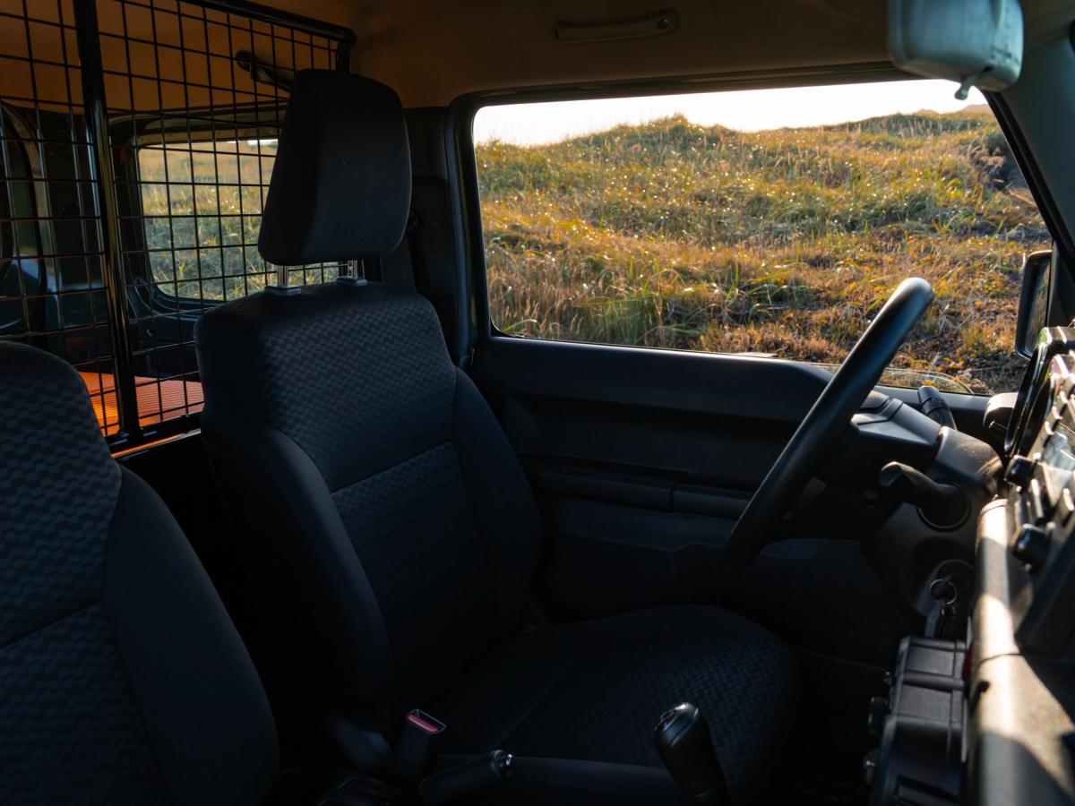 Jimny-Vordersitze Suzuki Jimny mit manuell verstellbaren Vordersitzen, Lenkrad und Laderaumtrenngitter hinter den Sitzen