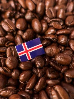 a small flag of iceland is sitting on top of a pile of coffee beans .