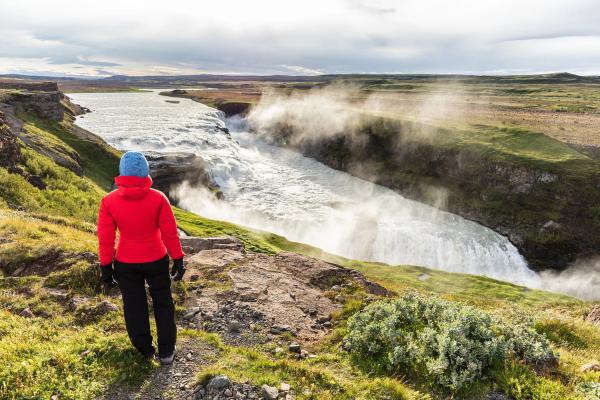 chica vestida en capas contemplando la cascada Gullfoss en Islandia