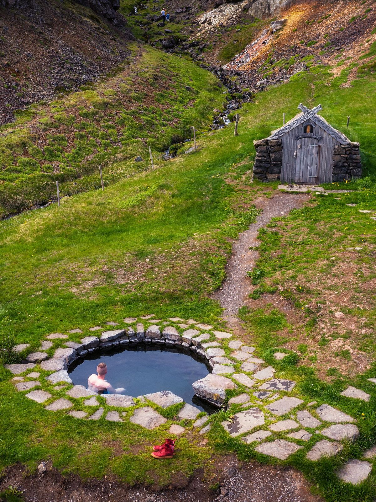 a man is taking a bath in a hot spring in the middle of a field .