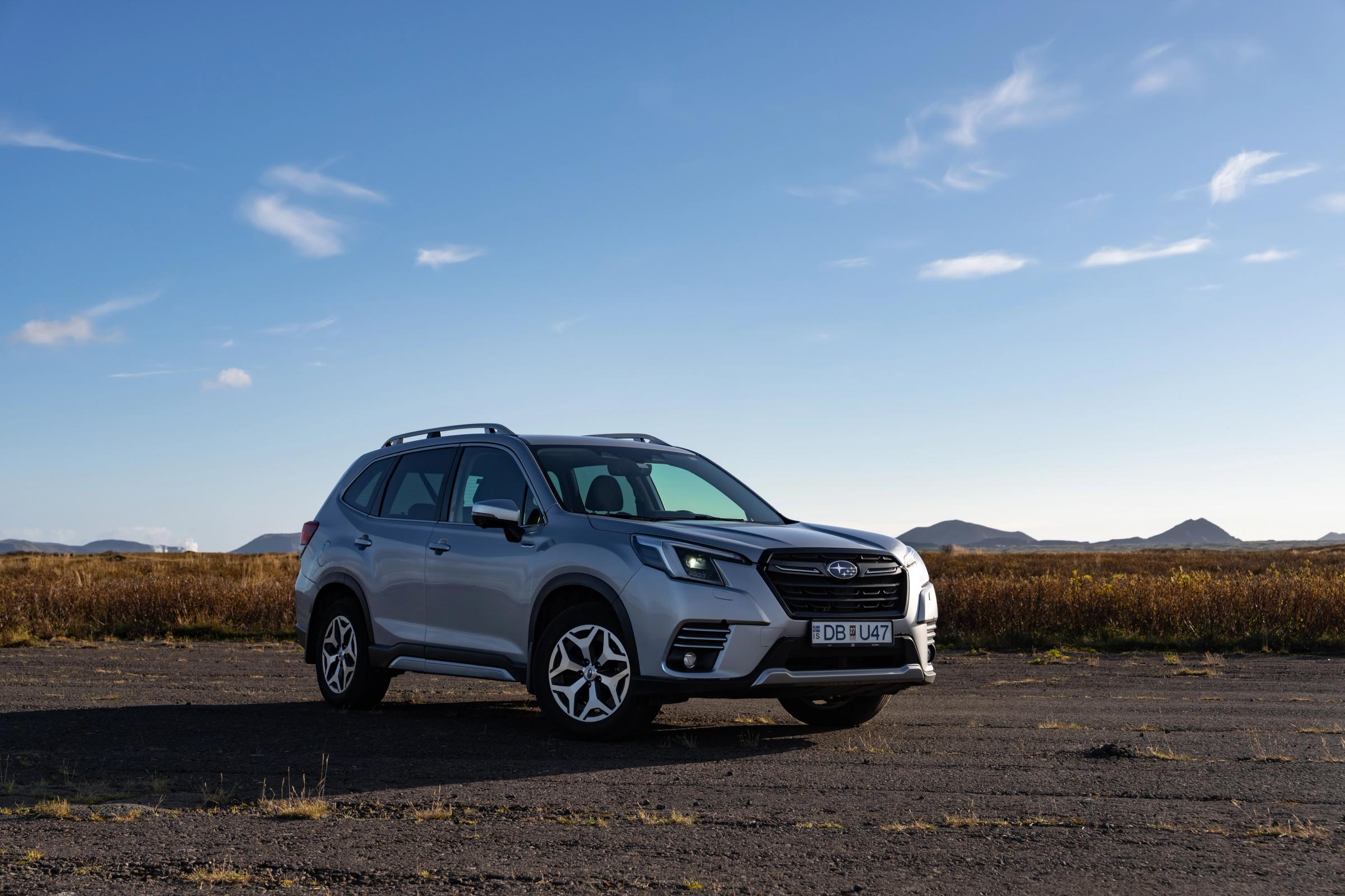 Silver Subaru Forester front three-quarter view on open ground with distant mountains behind