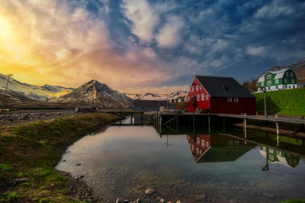 una casa de madera roja junto a un cuerpo de agua al atardecer