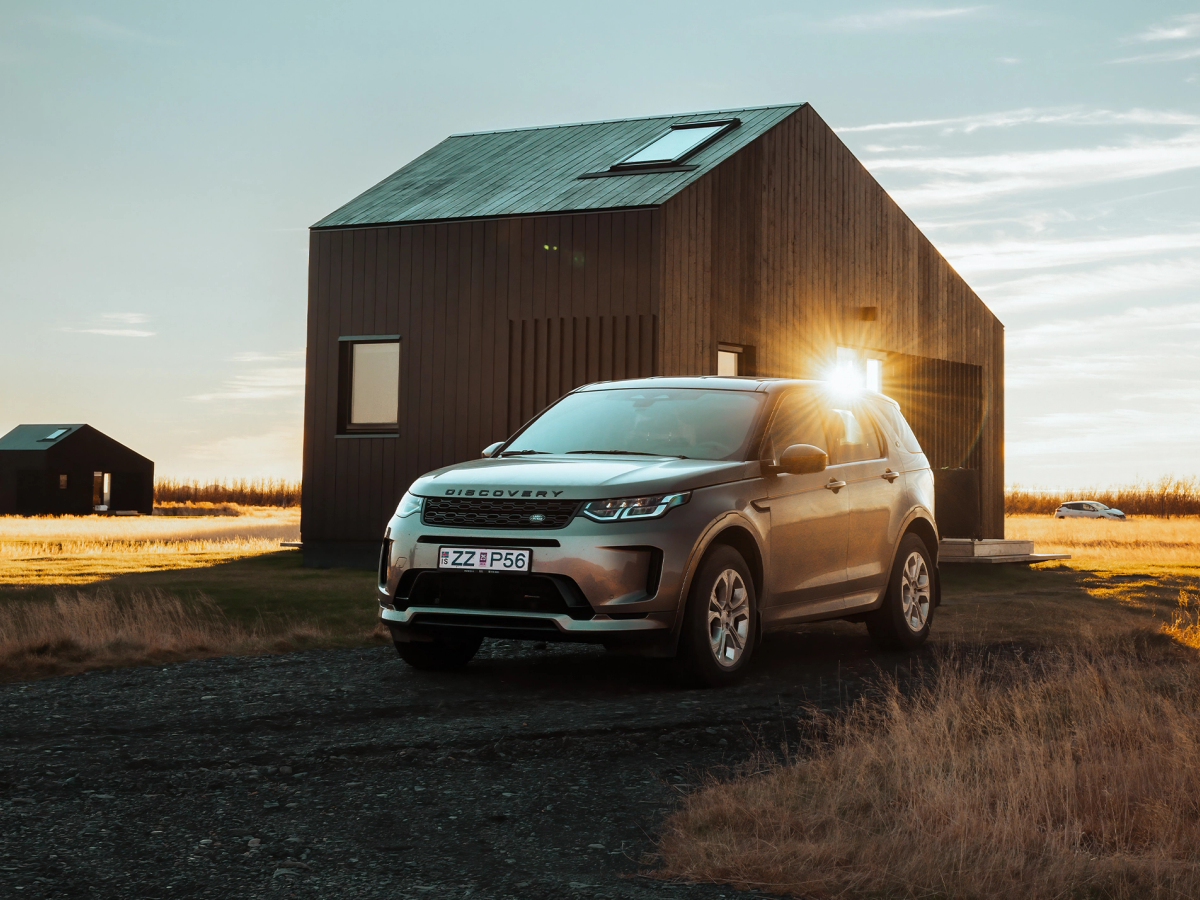 Discovery Sport – Vorderansicht vor einem Haus Land Rover Discovery Sport 4x4, geparkt neben einer modernen Hütte