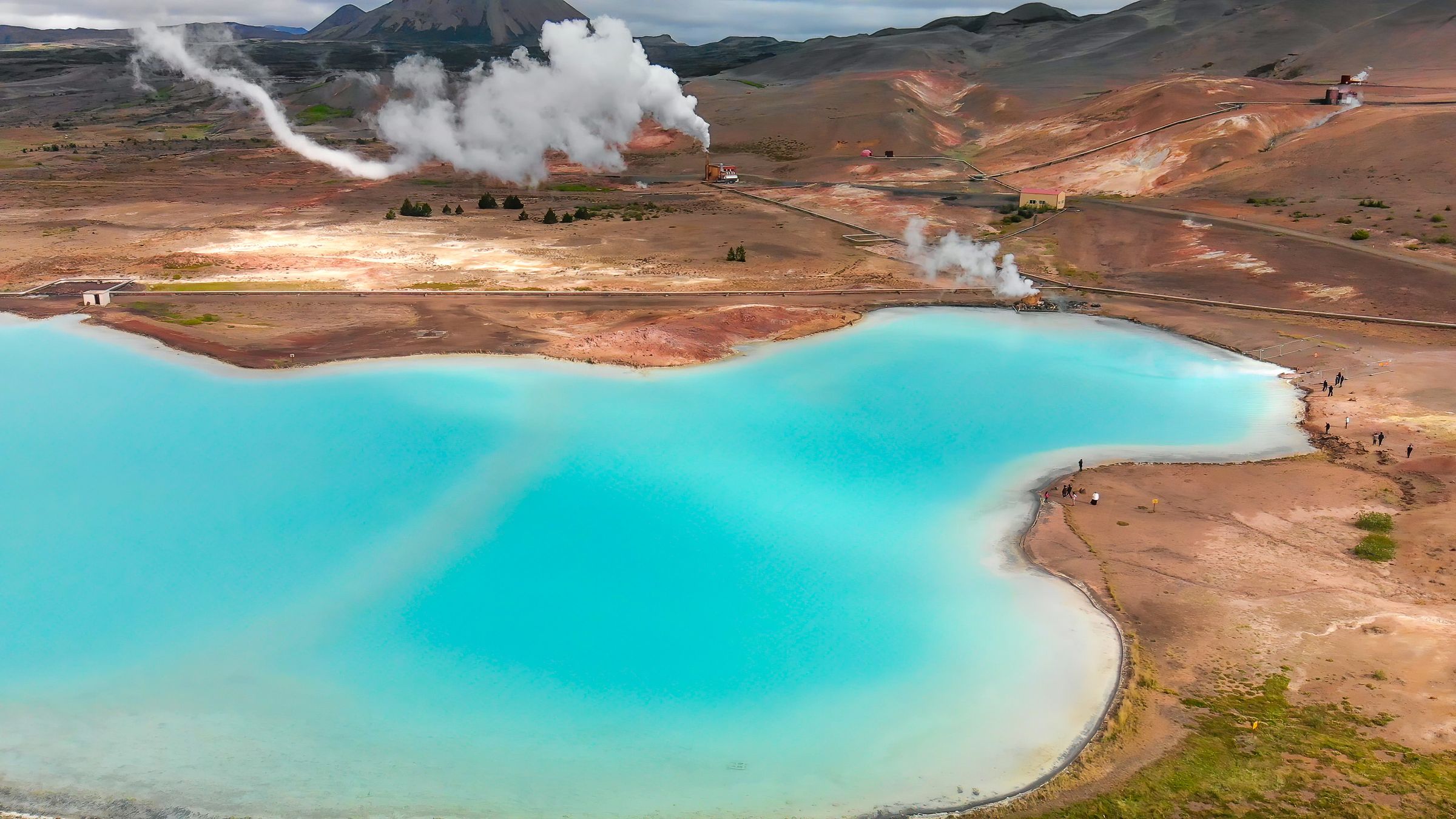 fumarolas naturales al lado de un lago de agua azul turquesa