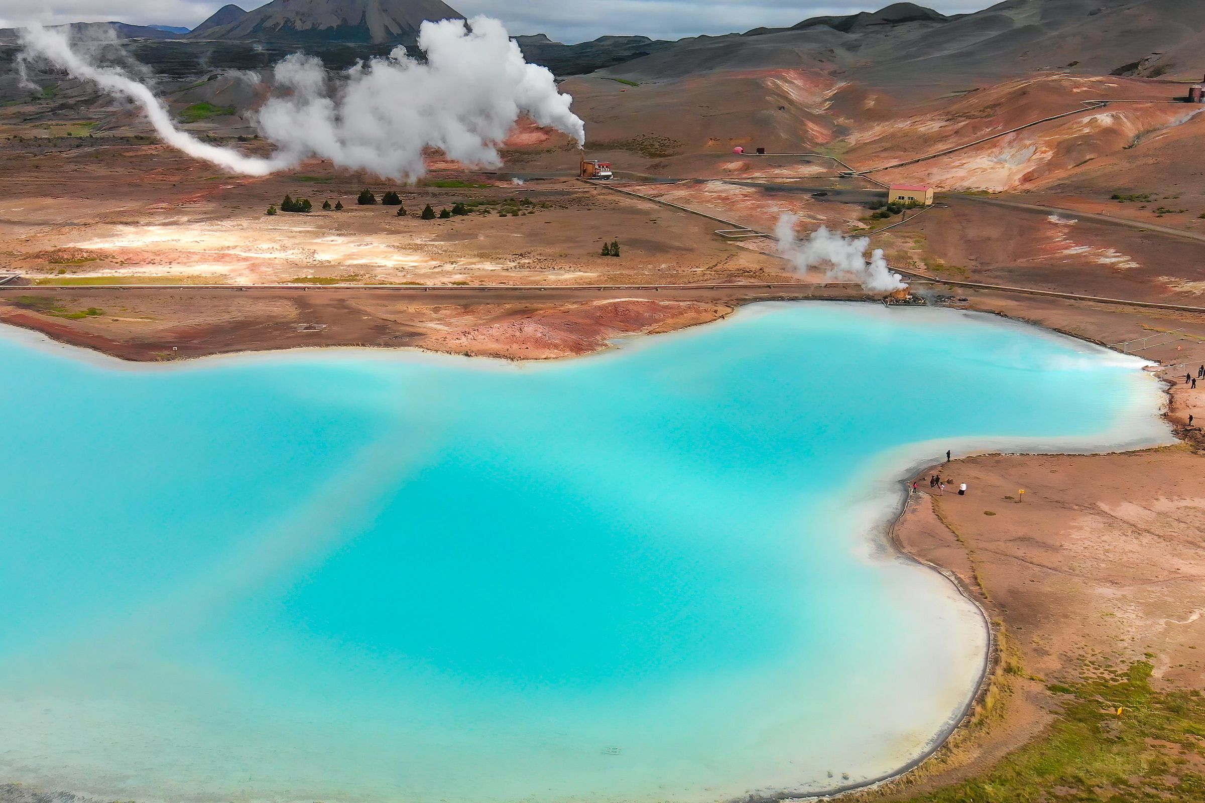 fumarolas naturales al lado de un lago de agua azul turquesa