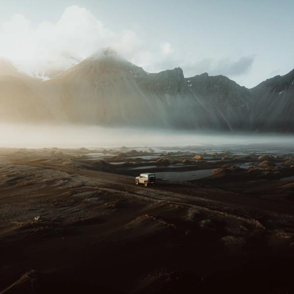 una vista aérea de un coche conduciendo por un camino de tierra en las montañas.