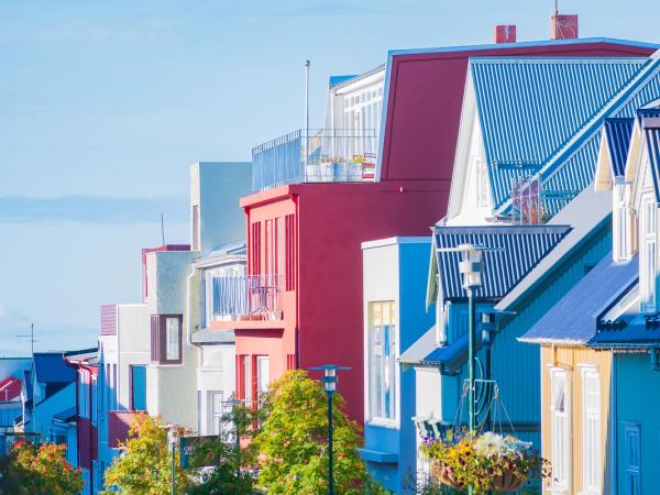 a row of colorful houses with blue roofs on a sunny day .