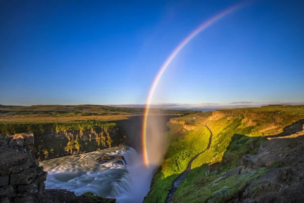 a waterfall with a double rainbow in the sky .
