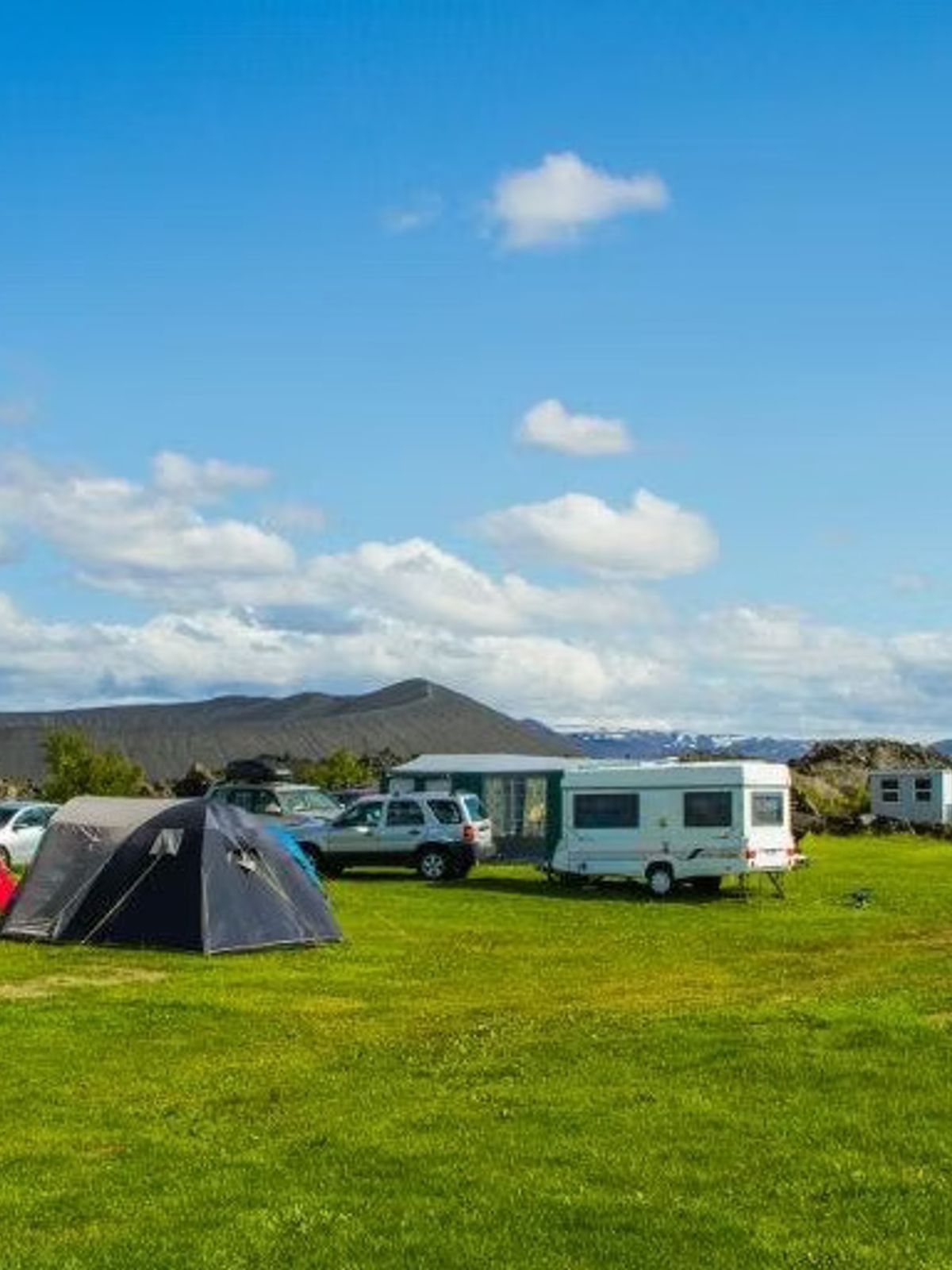 un grupo de tiendas de campaña y caravanas están estacionadas en un campo cubierto de hierba.