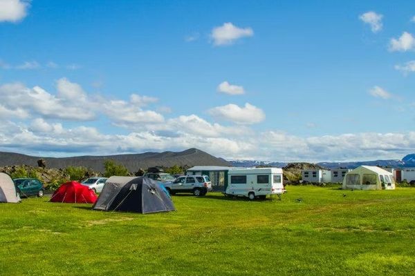 a group of tents and caravans are parked in a grassy field .