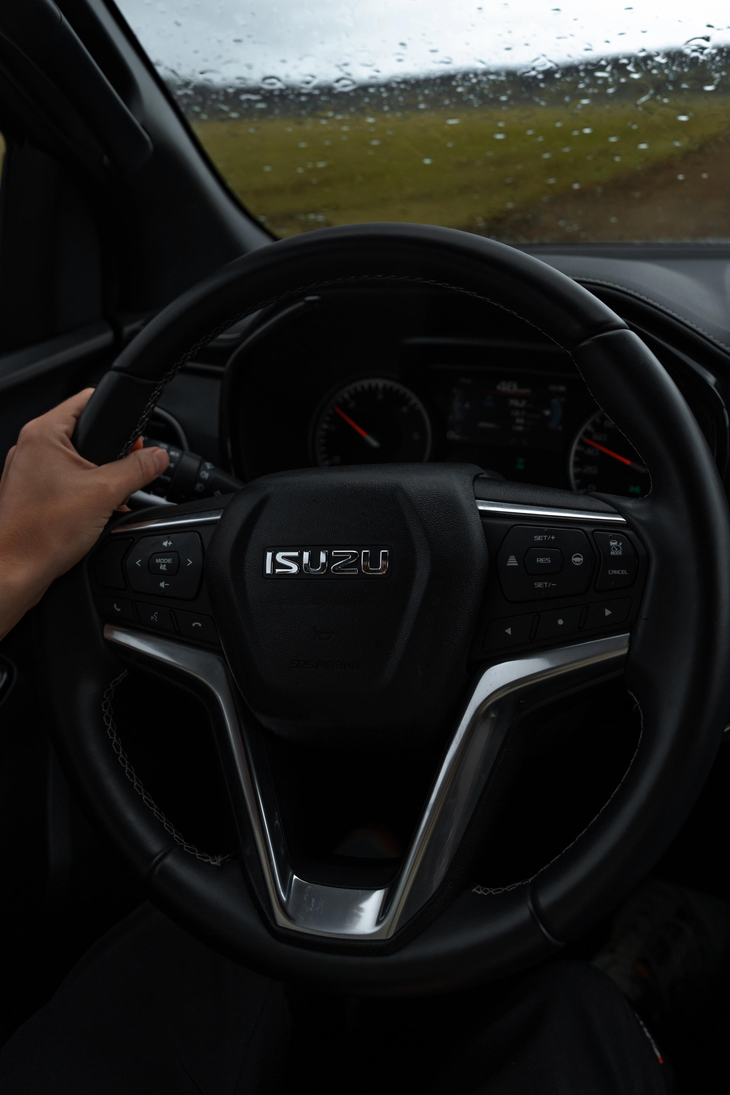 Funda para volante Mano con una manga de punto sobre el volante y un camino de grava visible al frente
