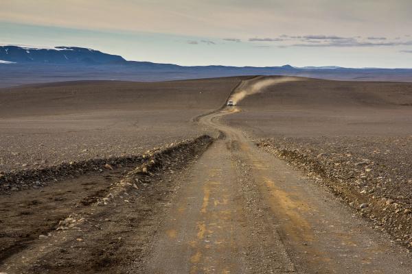 a car is driving down a dirt road in the desert .