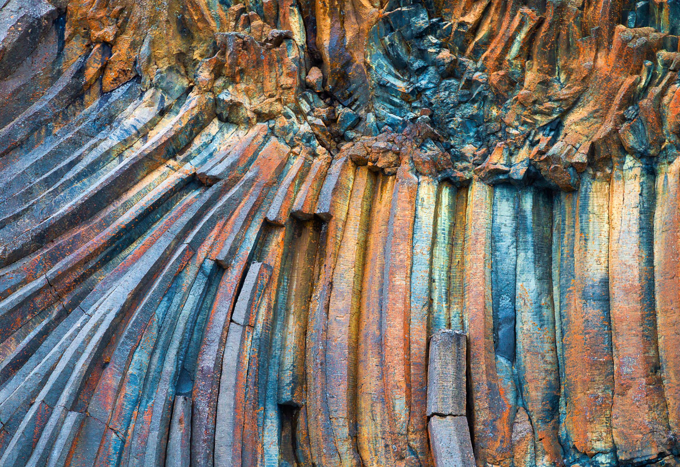 Curved and vertical basalt columns in blue, orange, and brown.