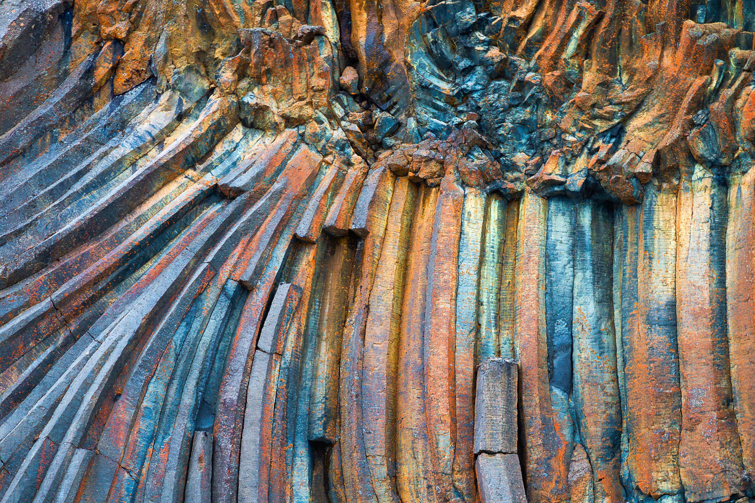 Curved and vertical basalt columns in blue, orange, and brown.