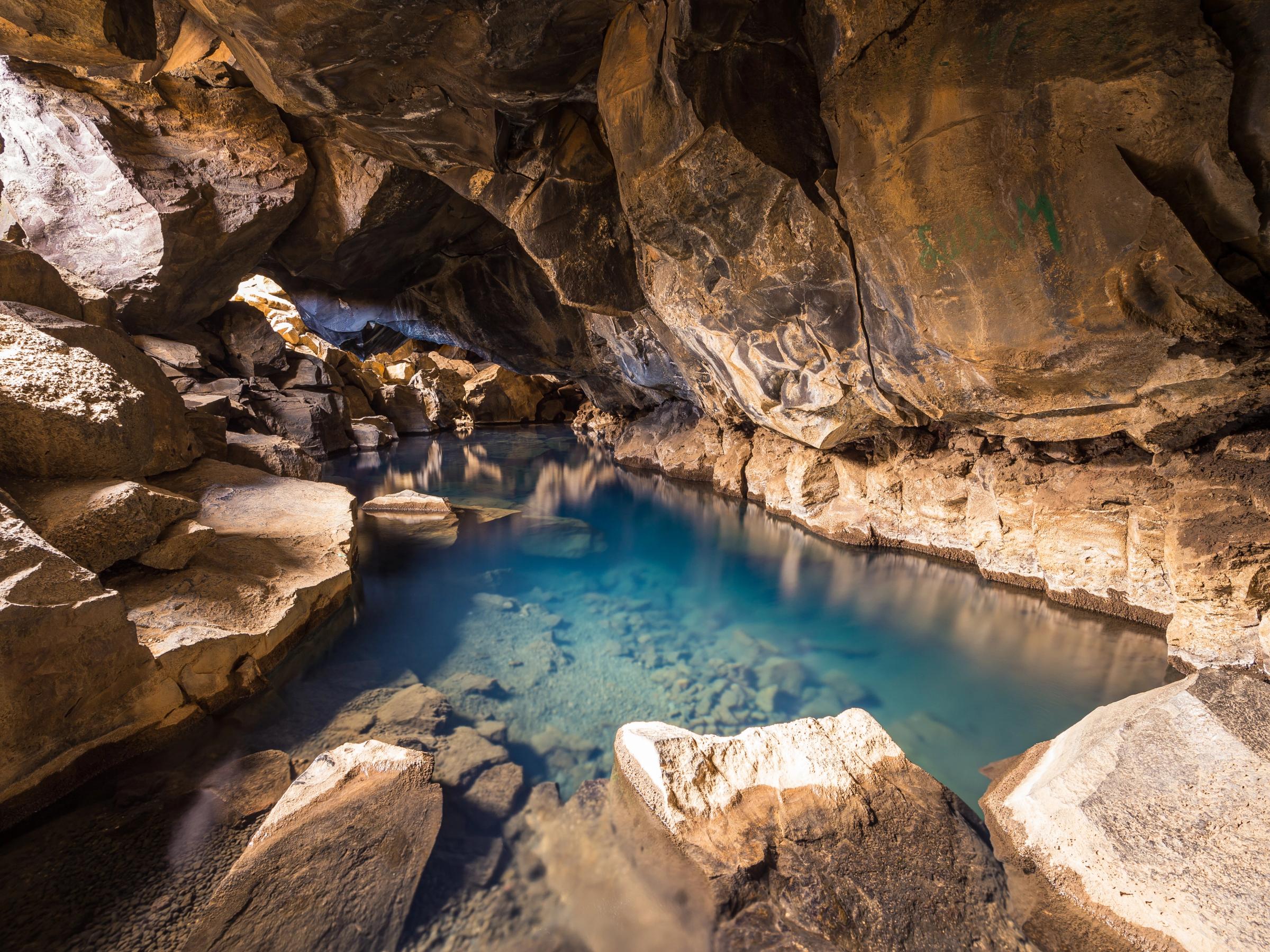 Clear blue water in a rocky cave.