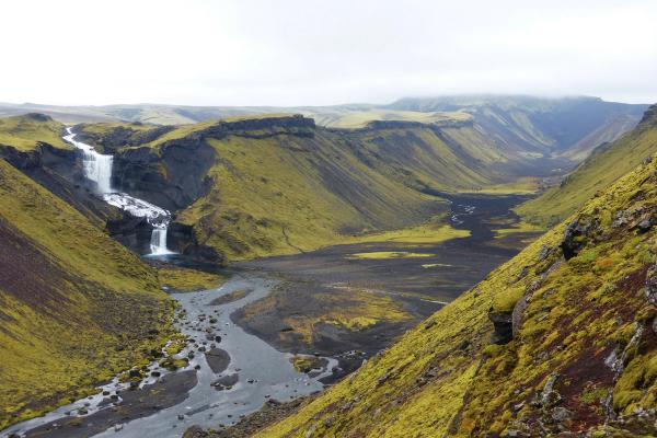 Moss-covered valley with a tiered waterfall and dark river.