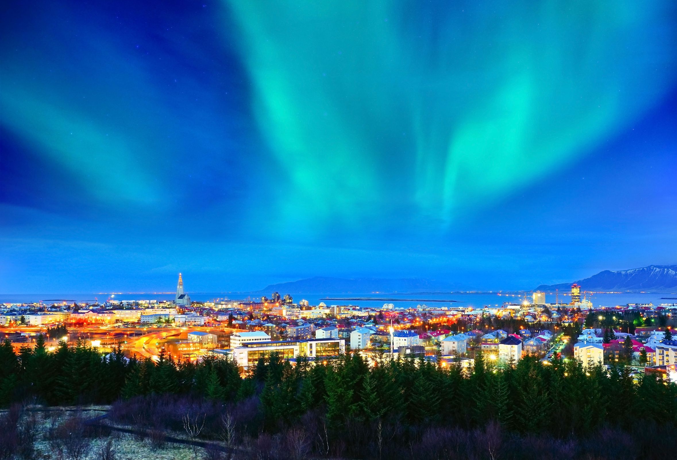the northern lights are shining over a city at night .