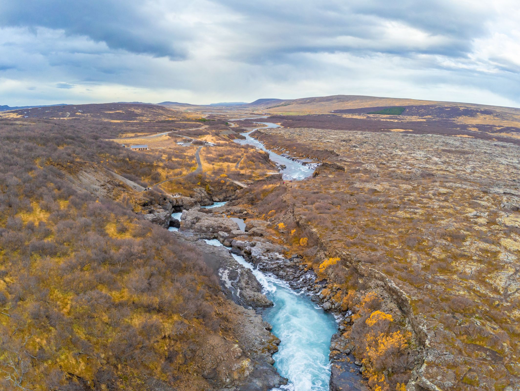 Aerial view of a river with some rapids surrounded by an autumn landscape