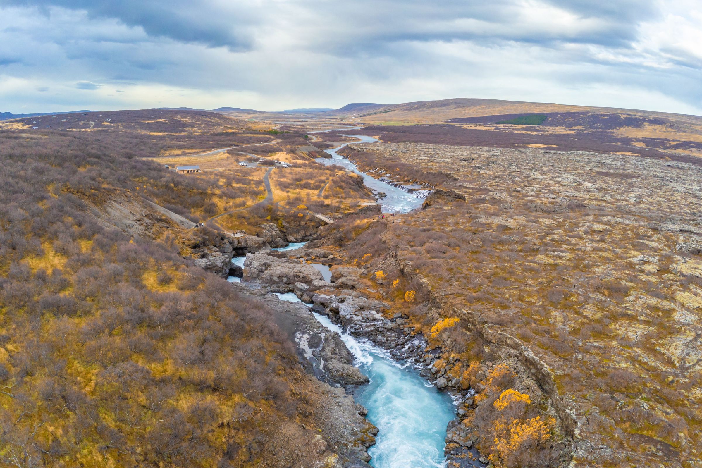 Aerial view of a river with some rapids surrounded by an autumn landscape