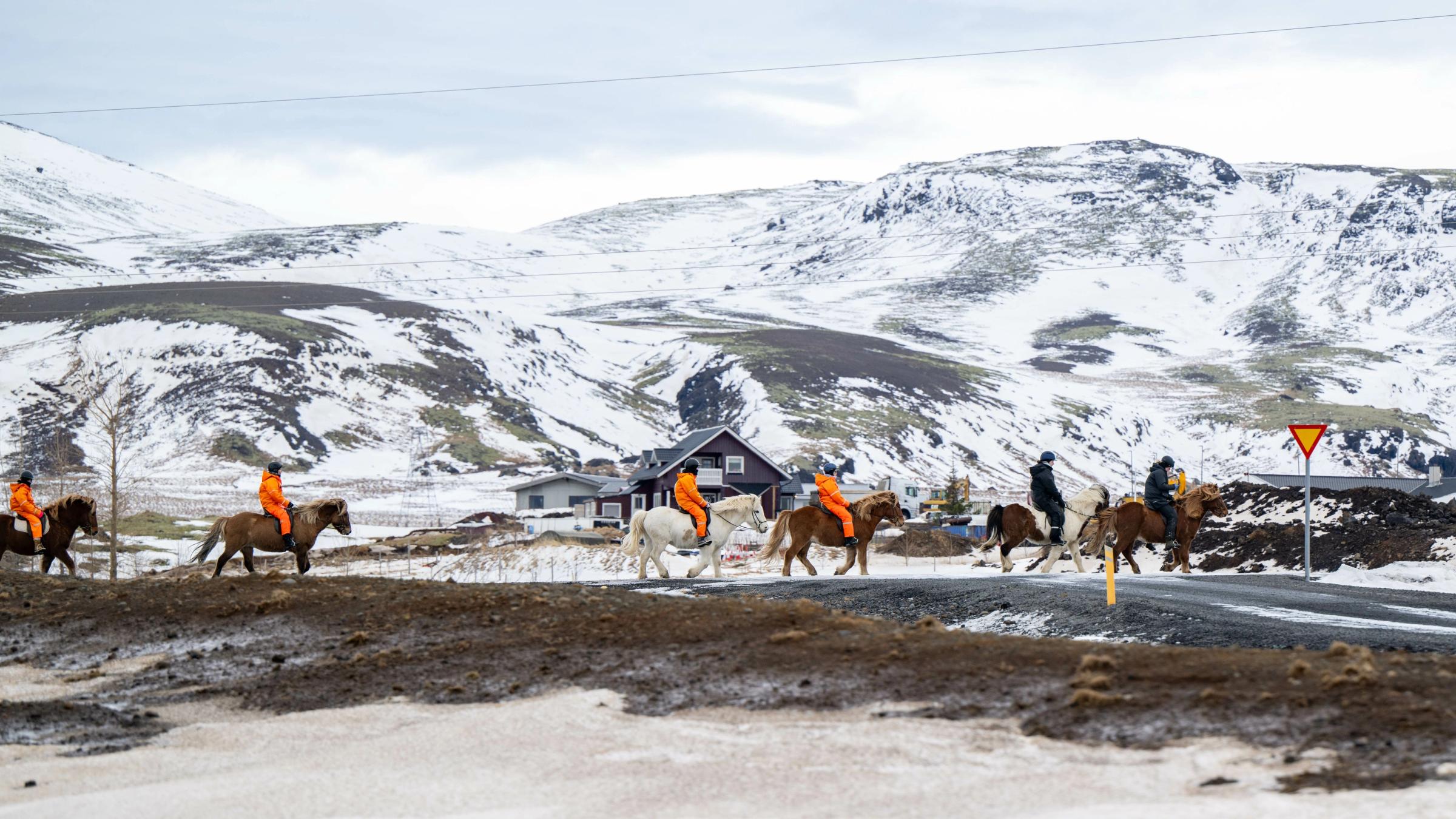 un grupo de personas montando a caballo con montañas nevadas detrás
