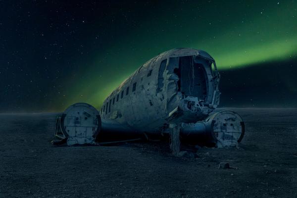 Abandoned DC Plane and Northern Lights in Iceland view on the famous DC plane abandoned in Iceland, and magnificent northern lights in a clear, blue and starry sky