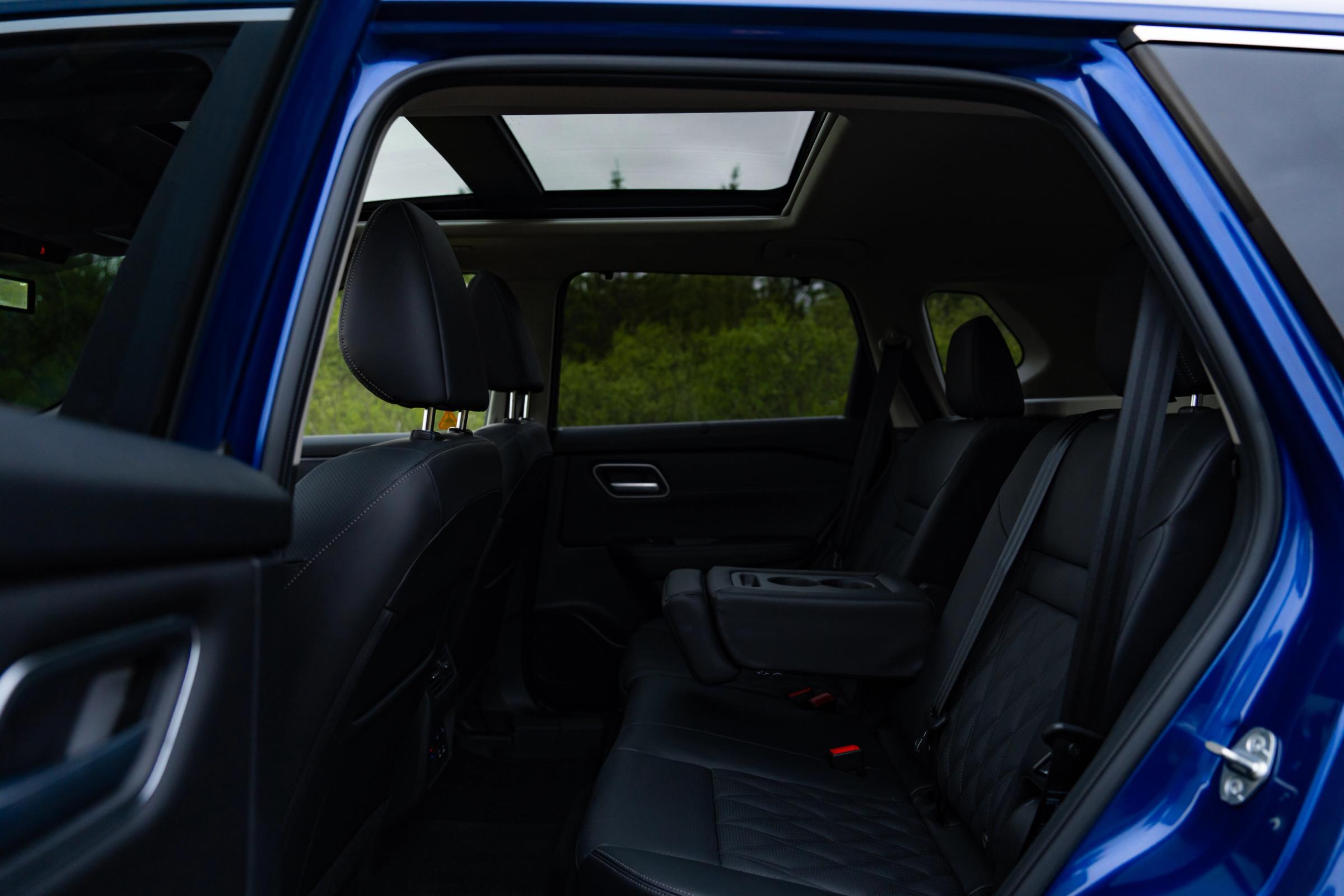 Vista del interior de un Nissan X-Trail, con los asientos traseros vistos a través de la puerta abierta y el techo solar visible