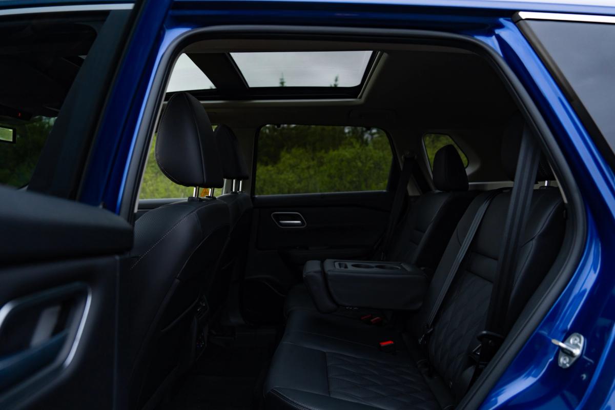 Vista del interior de un Nissan X-Trail, con los asientos traseros vistos a través de la puerta abierta y el techo solar visible