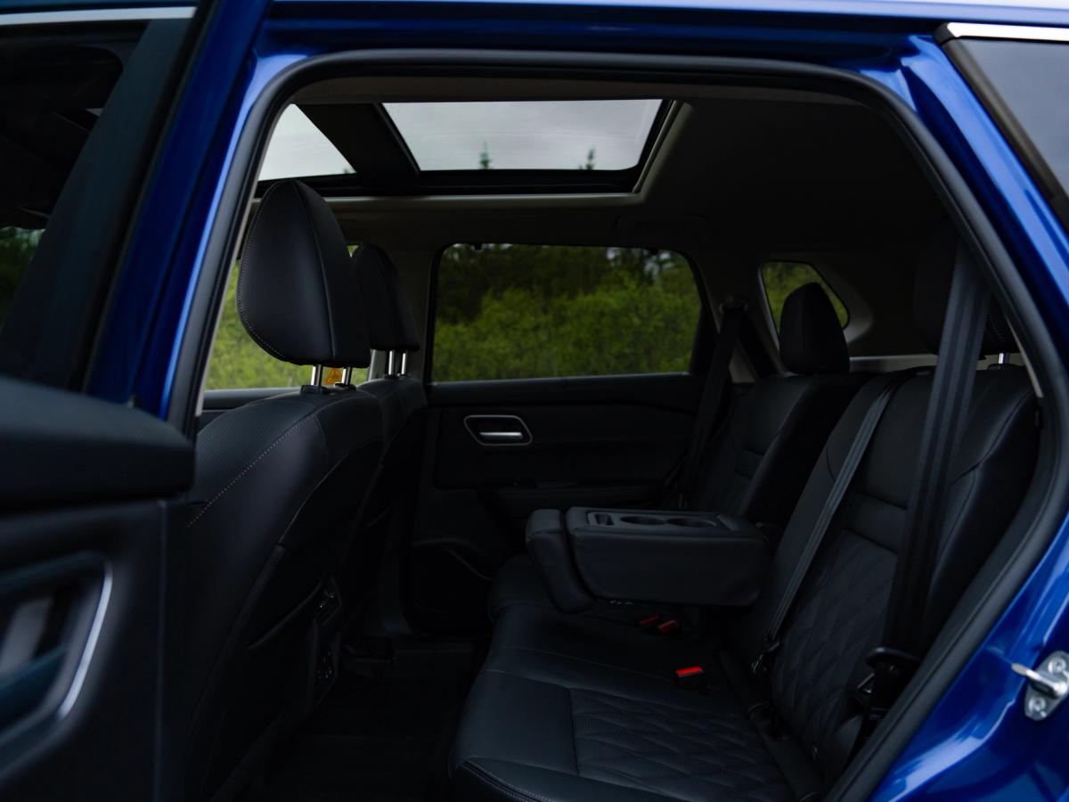 Vista de los asientos traseros del X-Trail Vista del interior de un Nissan X-Trail, con los asientos traseros vistos a través de la puerta abierta y el techo solar visible