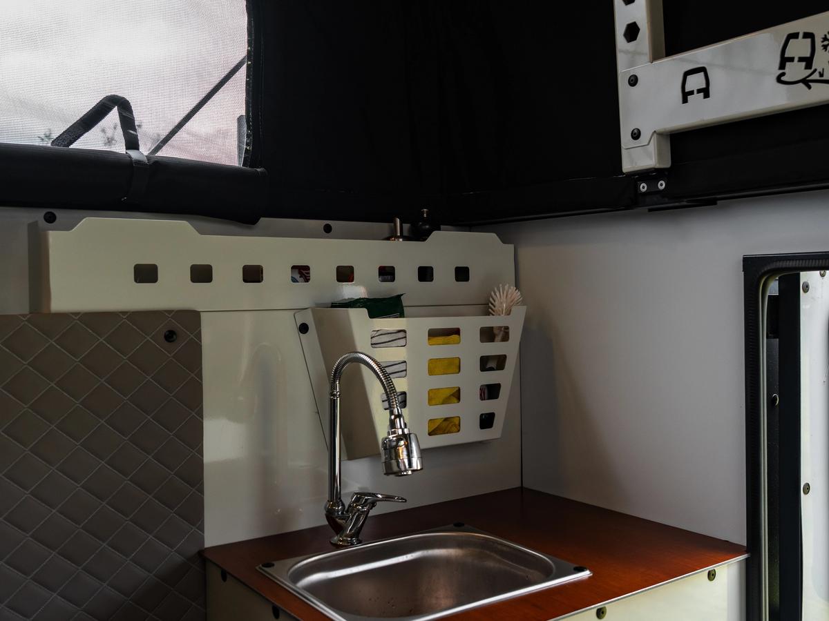 Lavabo y encimera Fregadero y grifo de acero inoxidable sobre una encimera de madera, con una cesta de almacenaje encima
