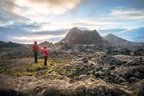 a man and a child are standing on top of a rocky hill holding hands .