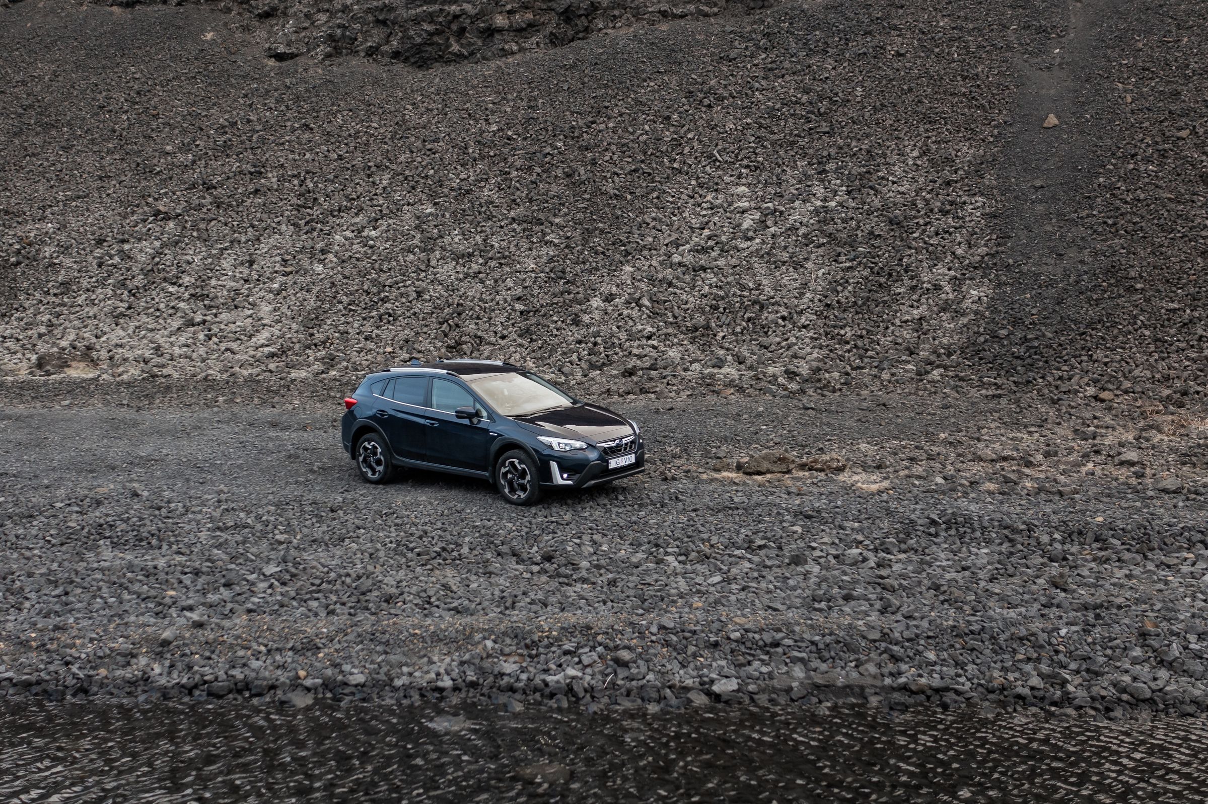 冰岛租赁的斯巴鲁 XV SUV 停在岩石坡前的碎石地面上