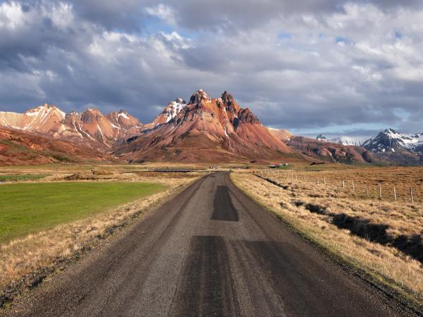 a road leading to a mountain range with pointy peaks