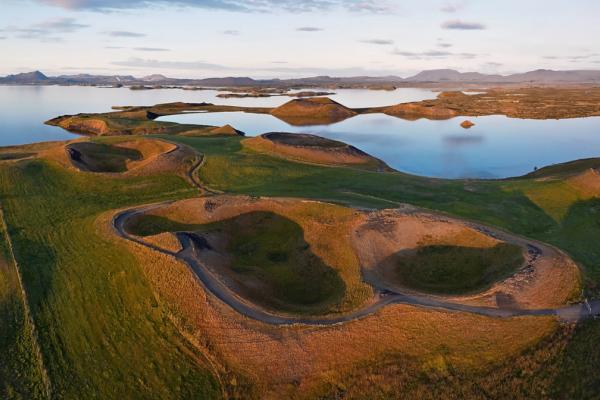 an aerial view of a lake surrounded by grassy hills and mountains at lake myvatn Iceland..