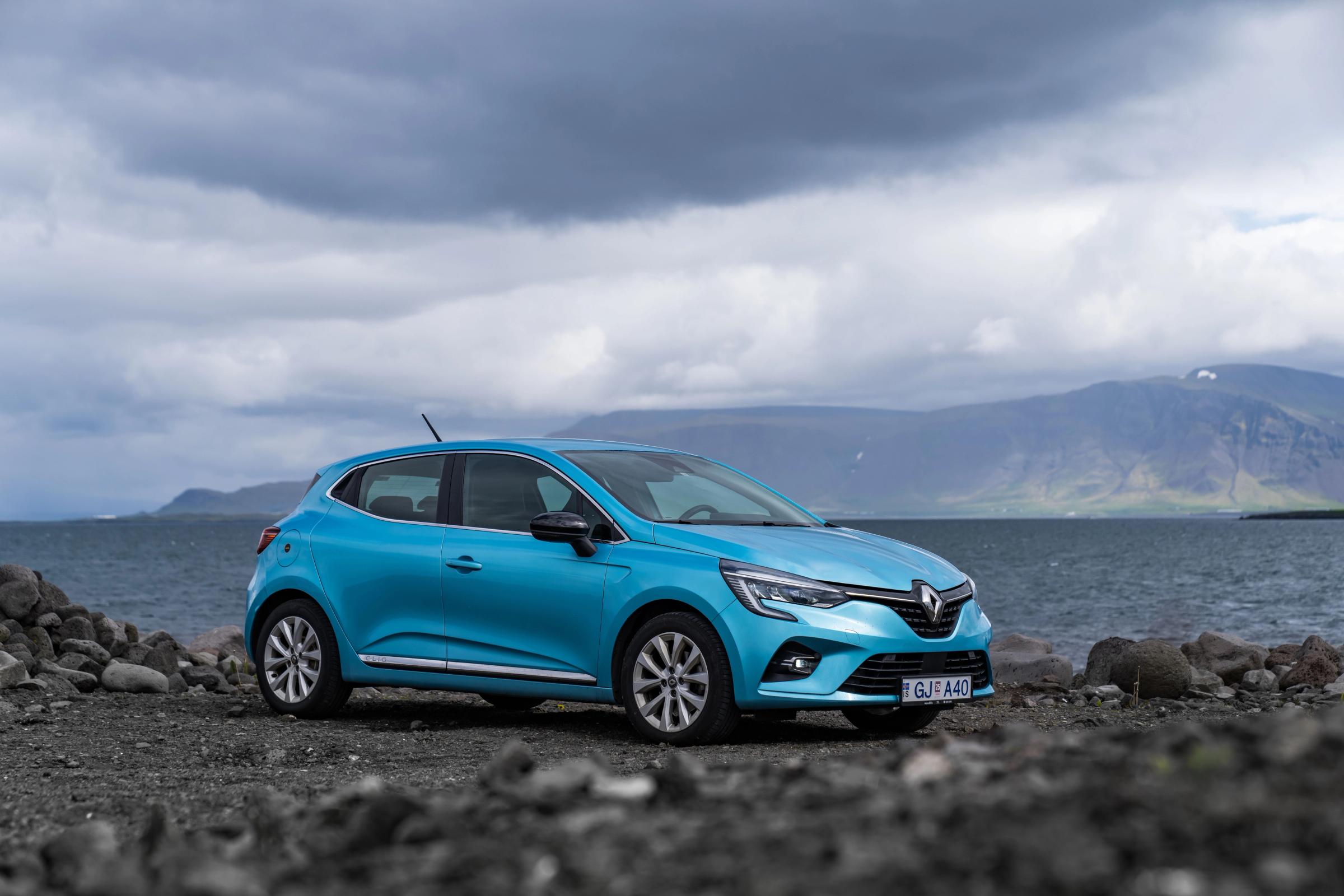 Clio – Vorderansicht schräg vor Küstenkulisse Kompaktwagen Renault Clio schräg von vorn, geparkt an einem felsigen Ufer mit Bergen im Hintergrund