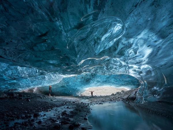 un hombre está de pie dentro de una cueva de hielo .