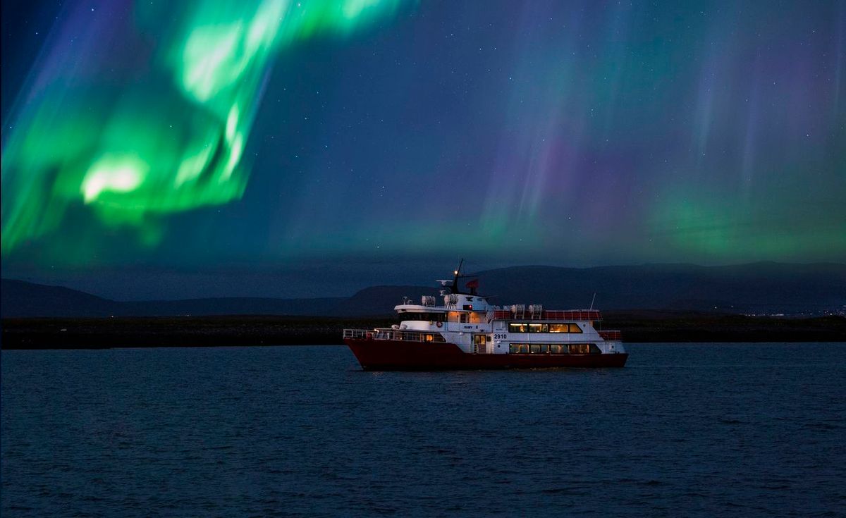 Un barco sobre el agua bajo la aurora boreal.