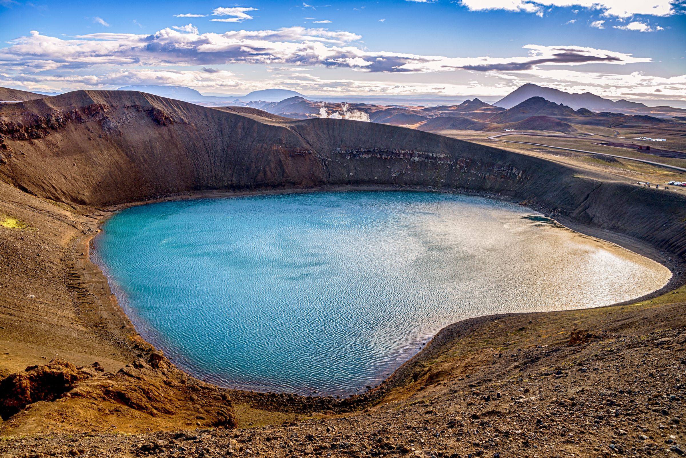 there is a large lake in the middle of a mountain at viti crater lake by lake myvatn in north iceland.