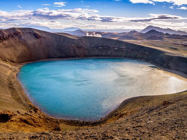 there is a large lake in the middle of a mountain at viti crater lake by lake myvatn in north iceland.