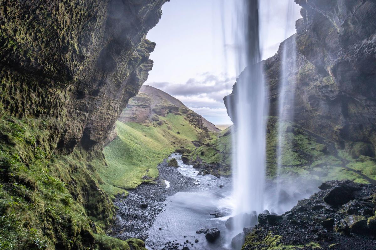 Cascada Kvernufoss vista desde atrás en un día soleado