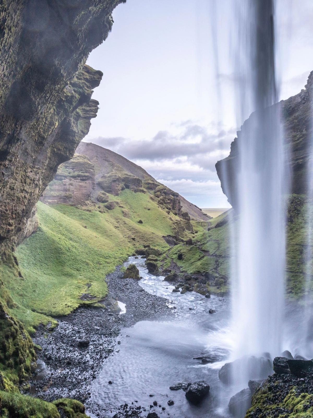 Cascada Kvernufoss vista desde atrás en un día soleado